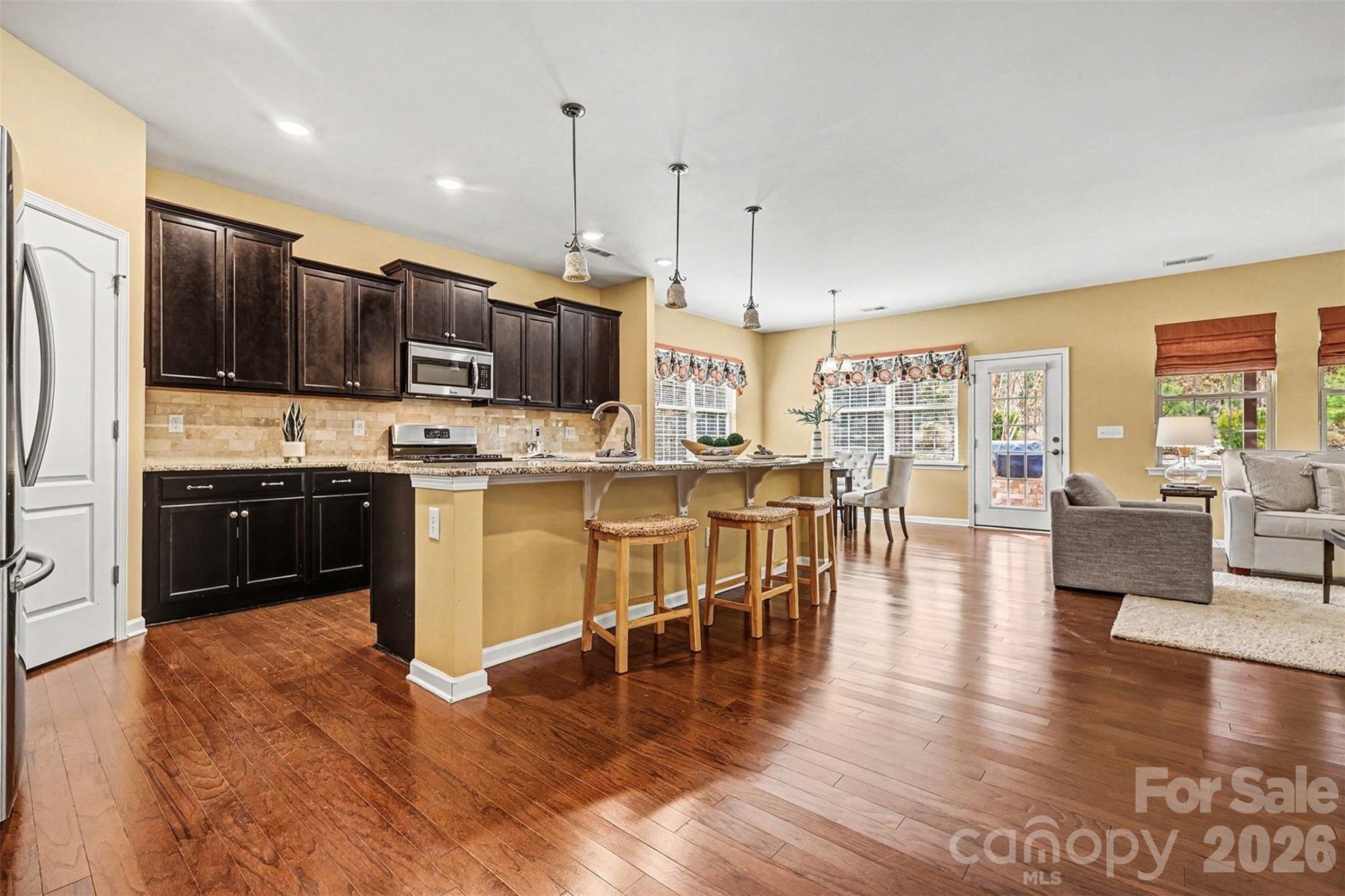 2192 Winhall Road Fort Mill, SC 29715 - Photo 5 of 32 a kitchen with stainless steel appliances granite countertop a stove top oven a sink dishwasher a dining table and chairs with wooden floor