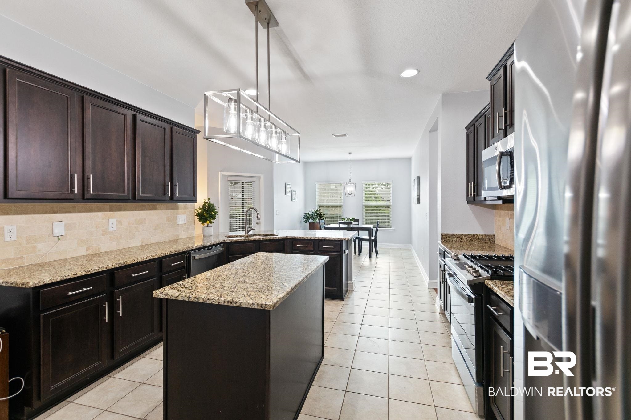 31541 Hoot Owl Road Daphne, AL 36527 - Photo 15 of 51 Kitchen featuring light stone counters, appliances with stainless steel finishes, decorative backsplash, decorative light fixtures, and sink