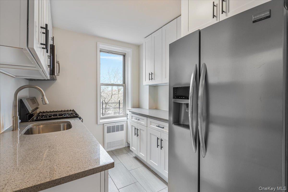59-30 108th Street, Unit 6D Queens, NY 11368 - Photo 17 of 23 a kitchen with white cabinets and stainless steel appliances
