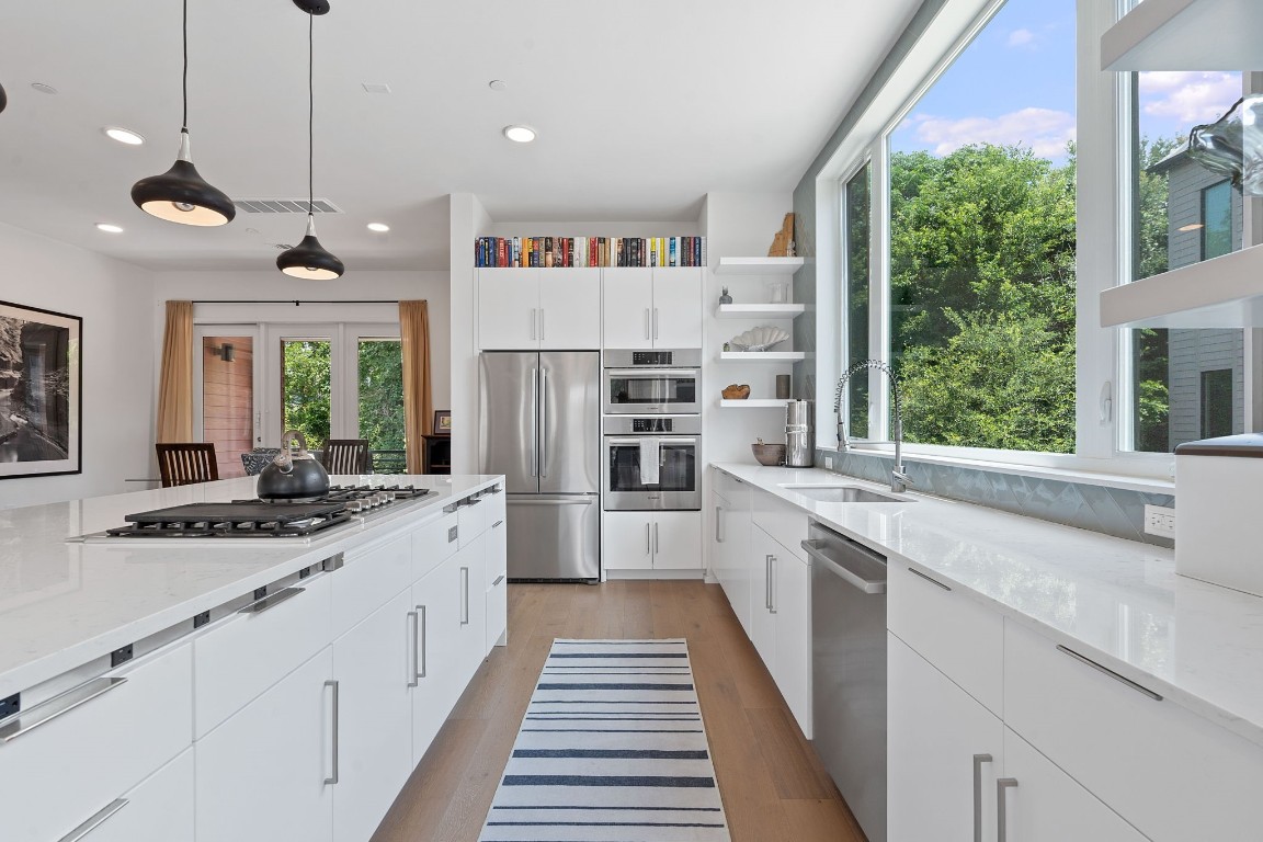 a large kitchen with kitchen island a large window a sink and stainless steel appliances