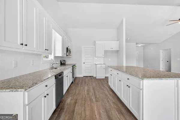 a large kitchen with granite countertop a sink a stove top oven a counter space and cabinets