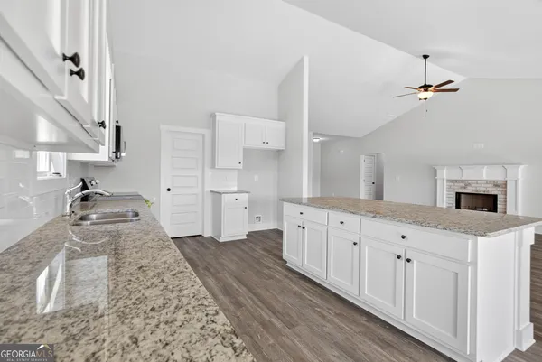 a large white kitchen with granite countertop a sink a stove a washer and dryer