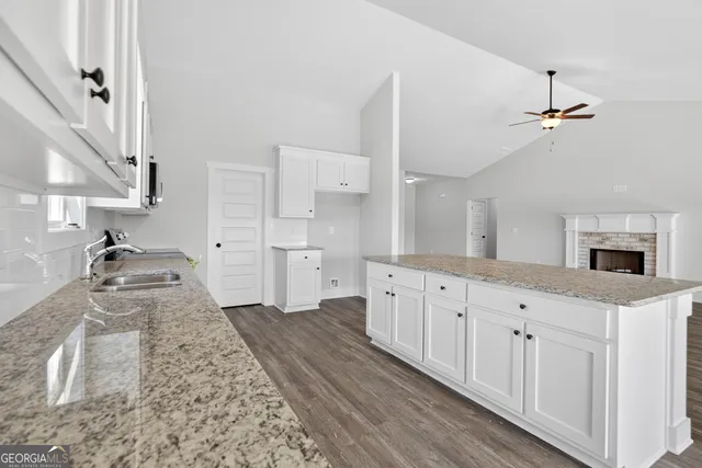 a large white kitchen with granite countertop a sink a stove a washer and dryer