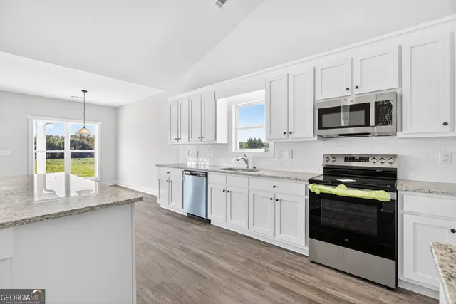 a kitchen with granite countertop cabinets stainless steel appliances and a counter space