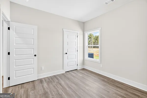 an empty room with wooden floor closet and windows