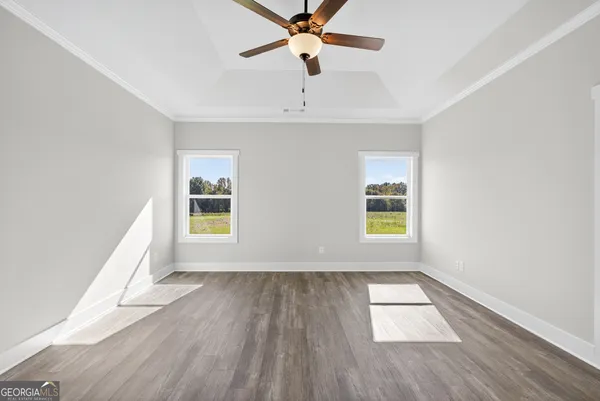 an empty room with wooden floor chandelier fan and windows