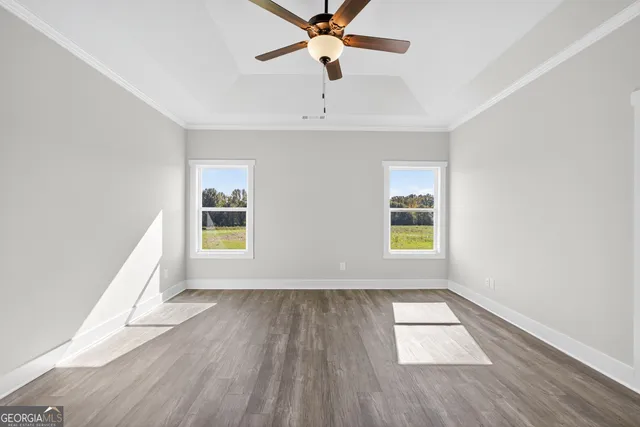 an empty room with wooden floor chandelier fan and windows