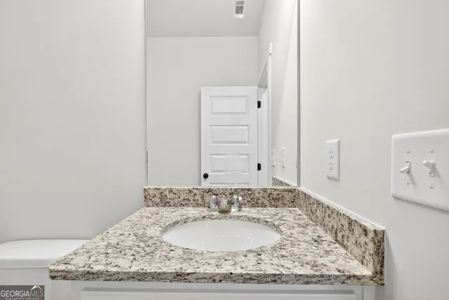 a bathroom with a granite countertop sink and a mirror