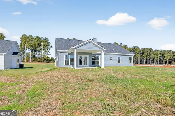 a front view of house with yard and trees in the background