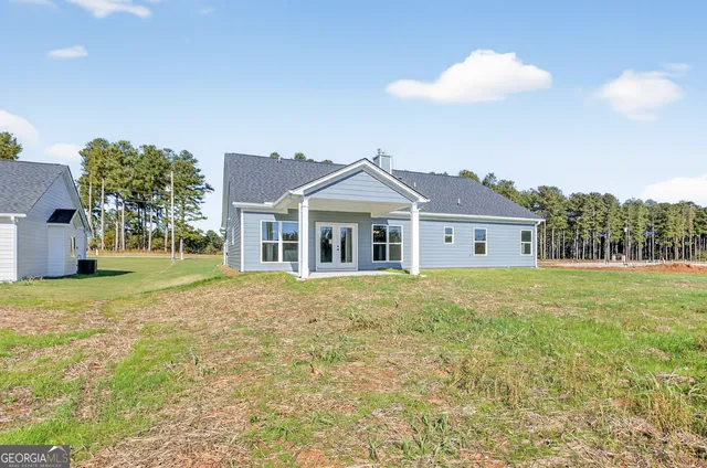 a front view of house with yard and trees in the background