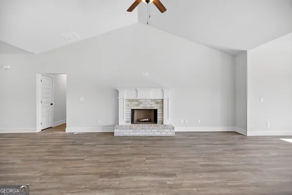 a view of an empty room with wooden floor fireplace and a window