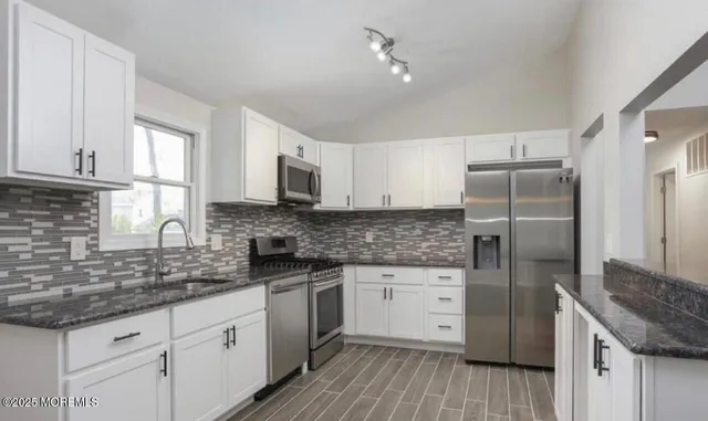 a kitchen with granite countertop a sink stainless steel appliances and cabinets