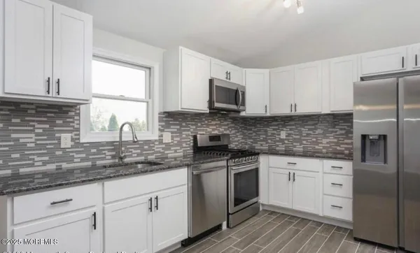 a kitchen with white cabinets sink and stainless steel appliances