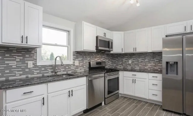 a kitchen with white cabinets sink and stainless steel appliances