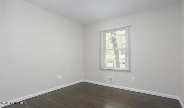 an empty room with wooden floor and a window