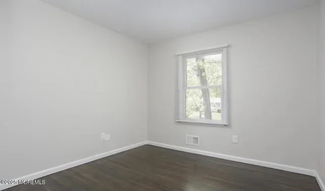 an empty room with wooden floor and a window