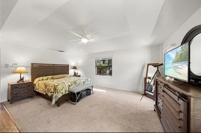a bedroom with a bed table flat screen tv and a window