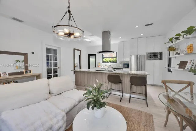 a living room with furniture kitchen view and a chandelier