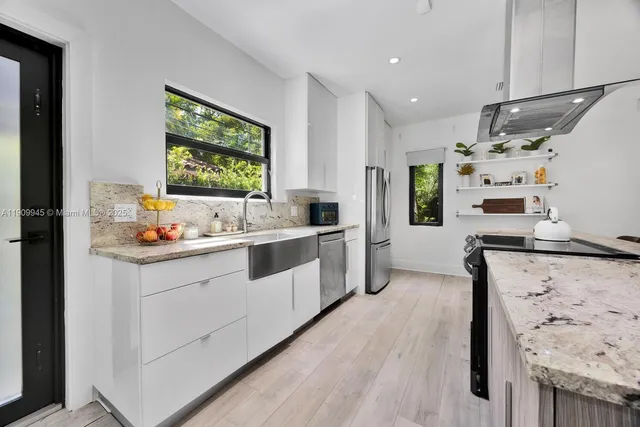 a kitchen with stainless steel appliances kitchen island granite countertop a sink stove and refrigerator