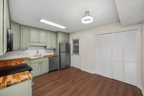 a kitchen with a sink a refrigerator and wooden floor