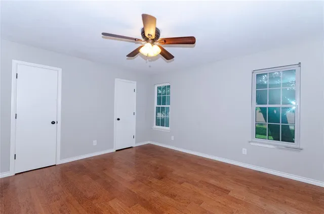 a view of empty room with wooden floor and window