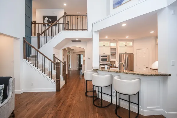 a dining hall with stainless steel appliances kitchen island a table chairs in it and wooden floors