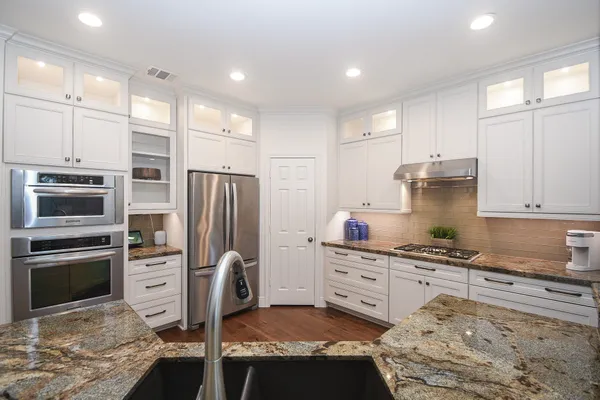 a kitchen with stainless steel appliances kitchen island granite countertop a refrigerator stove and sink