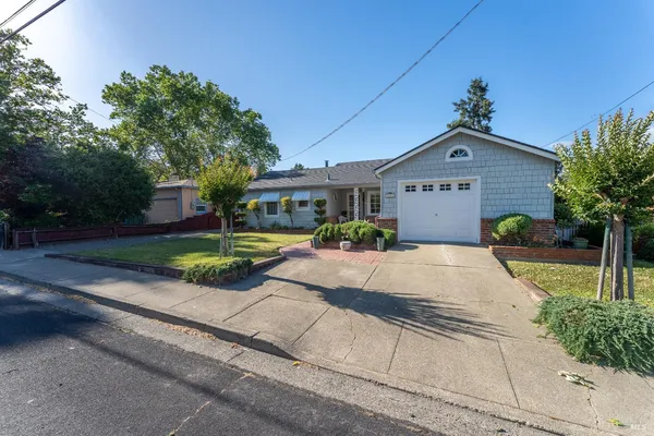 a front view of a house with a yard and potted plants