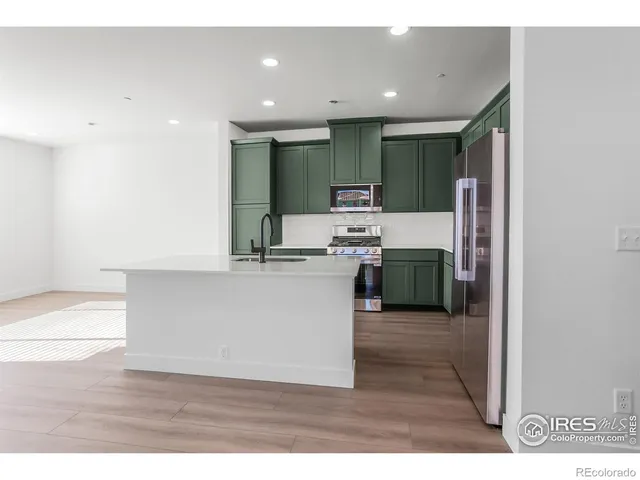a room with kitchen island stainless steel appliances a sink and cabinets