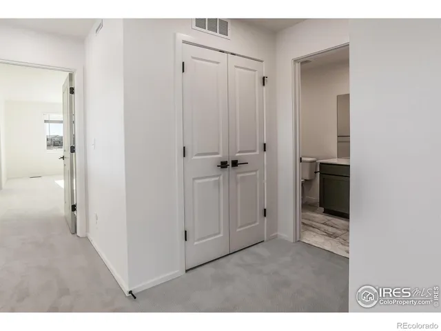 a view of a hallway with wooden floor and closet