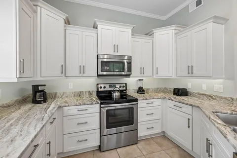 a kitchen with granite countertop white cabinets and stainless steel appliances