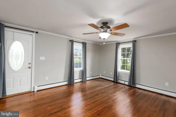 an empty room with wooden floor a ceiling fan and window