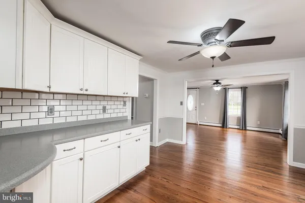 a kitchen with granite countertop a stove a sink and white cabinets with wooden floor next to windows