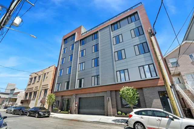 a front view of a building with lot of cars and trees