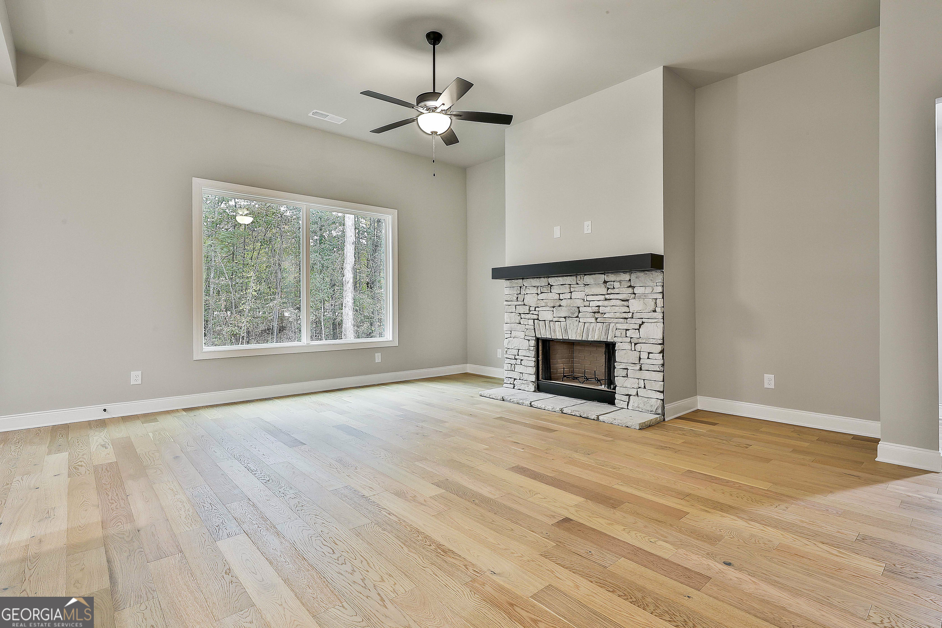 152 Wet Wood Drive, Unit 10 Fairburn, GA 30213 - Photo 15 of 39 an empty room with wooden floor fireplace cabinet and windows