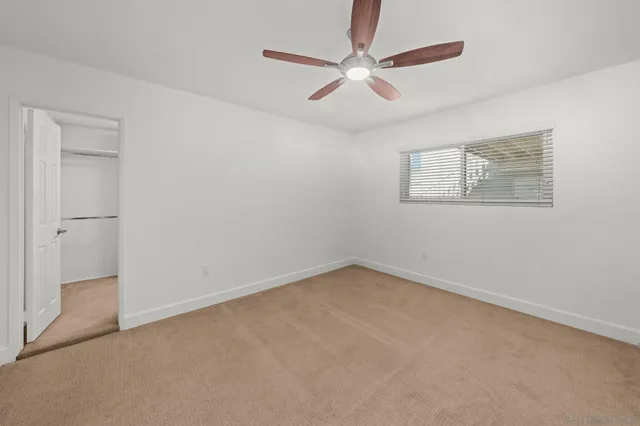 an empty room with a ceiling fan and a window