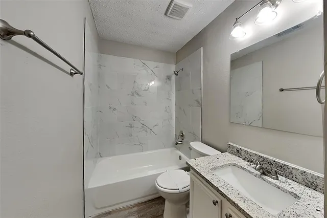 a bathroom with a granite countertop sink a toilet and shower