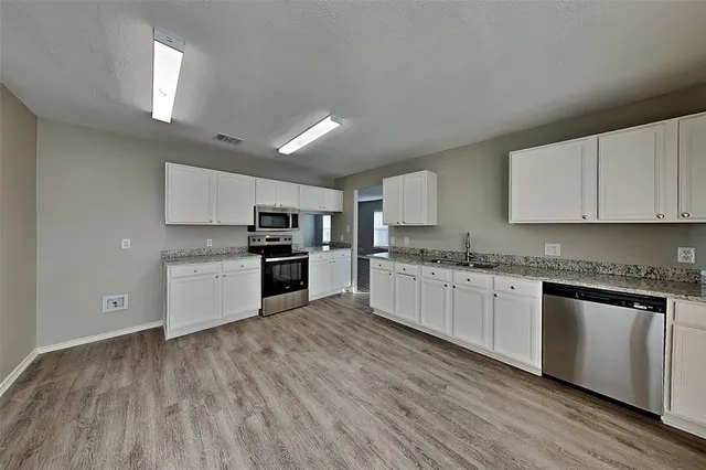 a kitchen with granite countertop white cabinets and stainless steel appliances
