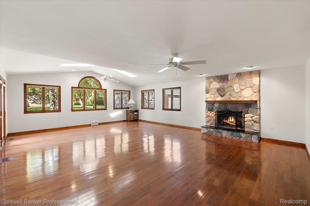 78 Carter Avenue Troy, MI 48098 - Photo 18 of 52 Unfurnished living room featuring hardwood / wood-style floors, plenty of natural light, a ceiling fan, a fireplace, and vaulted ceiling