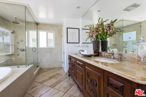 a spacious bathroom with a granite countertop sink a mirror a bathtub and shower
