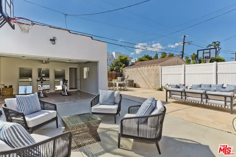 a view of a patio with couches table and chairs under an umbrella