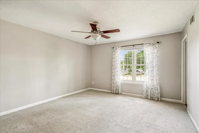 an empty room with windows and fan