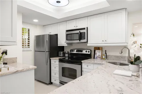 a kitchen with a sink a microwave a refrigerator and cabinets