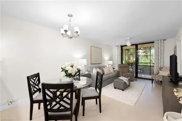 a view of a livingroom and a dining room with furniture a chandelier and wooden floor