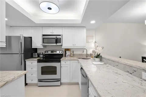 a kitchen with granite countertop a sink stove and refrigerator