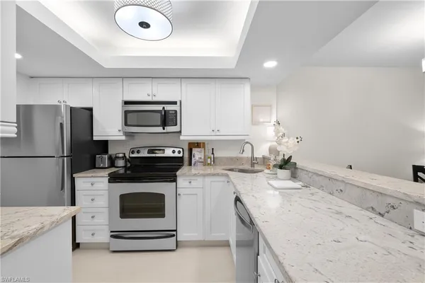 a kitchen with granite countertop a sink stove and refrigerator