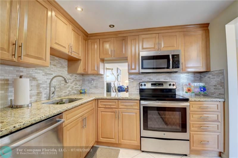 a kitchen with granite countertop a stove top oven sink and cabinets