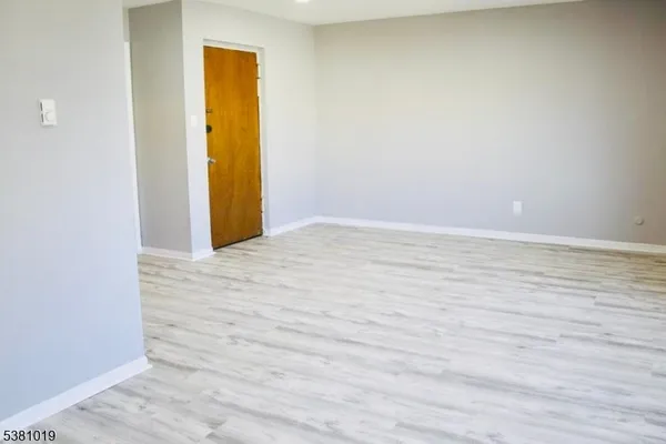 a view of a room with wooden floor and door