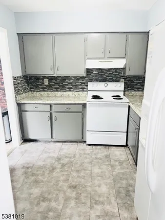 a kitchen with granite countertop a sink a stove and cabinets