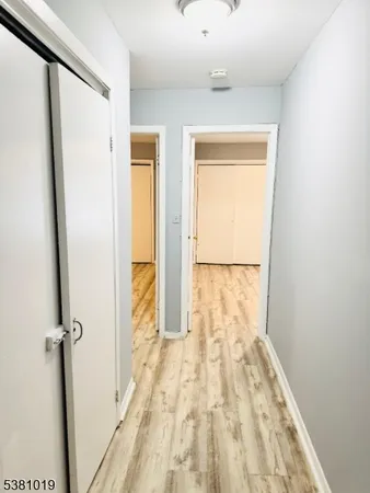 a view of a hallway with wooden floor and a bathroom